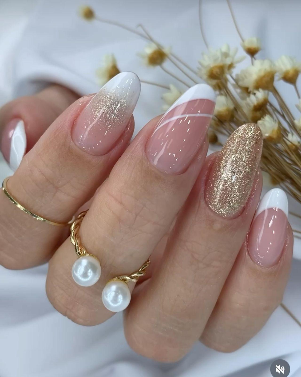 Almond nails with white French tips, gold glitter ombré and accent nail
