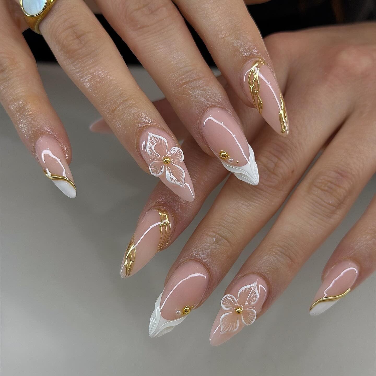 Stiletto nude nails with 3D white flowers, gold chrome lines and white tips