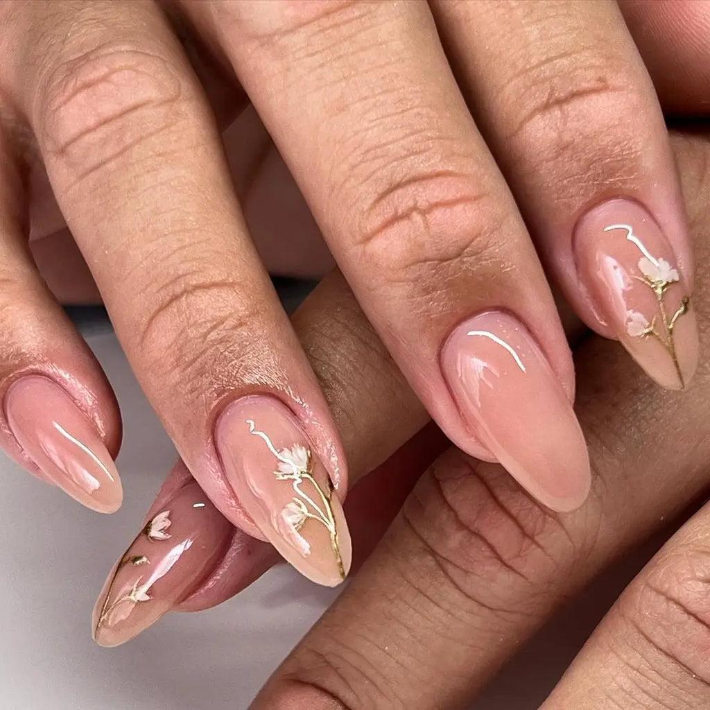 Almond nude nails with white flowers and gold stems