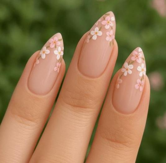 Pointed nude nails with pink and white flowers at the tips