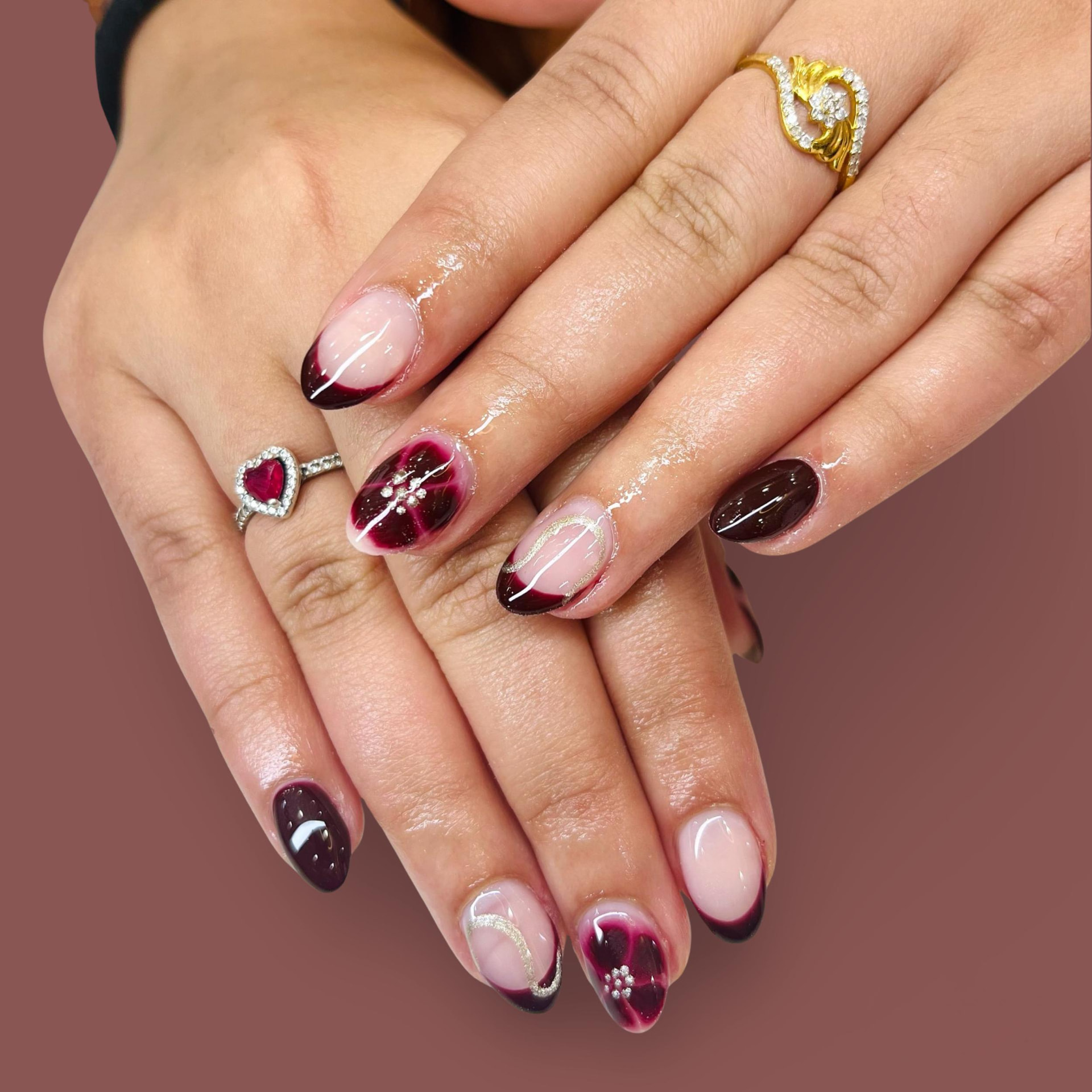 Short almond nails with berry aura, dark French tips and stone accents